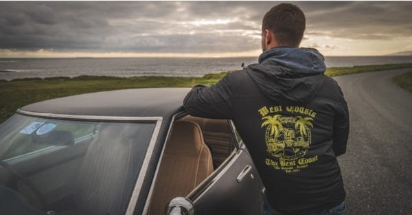 Person standing beside car with sun setting on the sea modelling Rossnowlagh Surf School Light Active Jacket