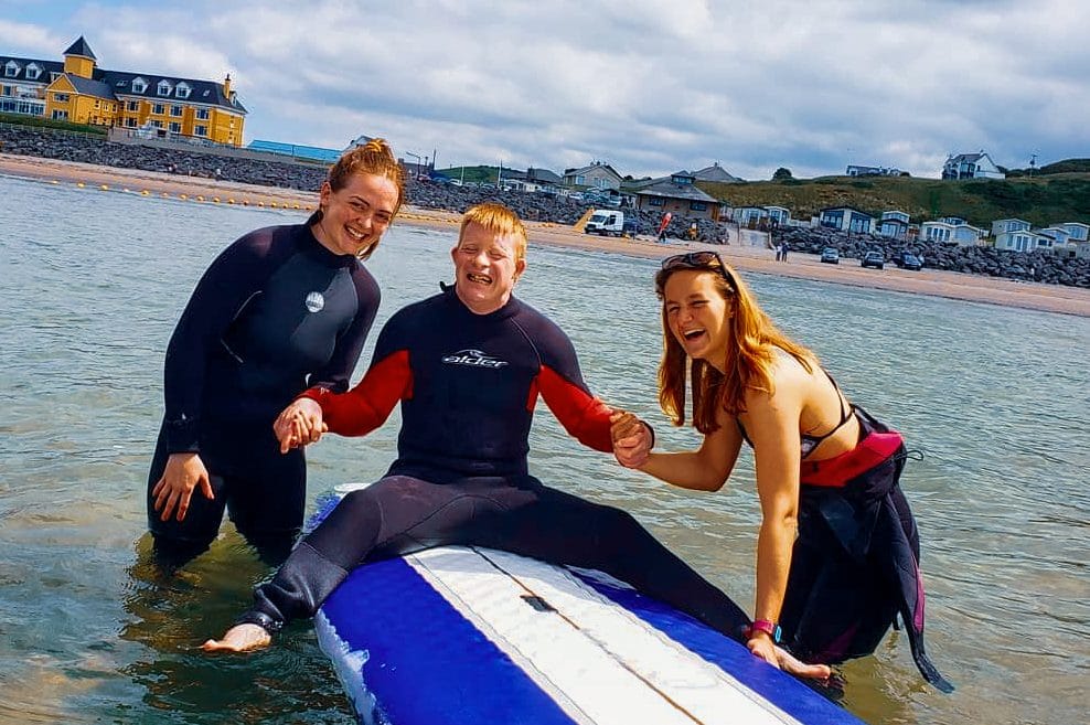 student and instructors posing during Inclusive surf lesson