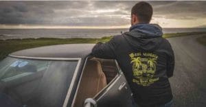 Person standing beside car with sun setting on the sea modelling Rossnowlagh Surf School Light Active Jacket