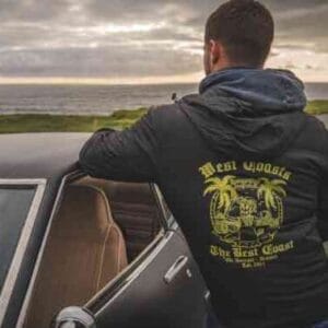 Person standing beside car with sun setting on the sea modelling Rossnowlagh Surf School Light Active Jacket